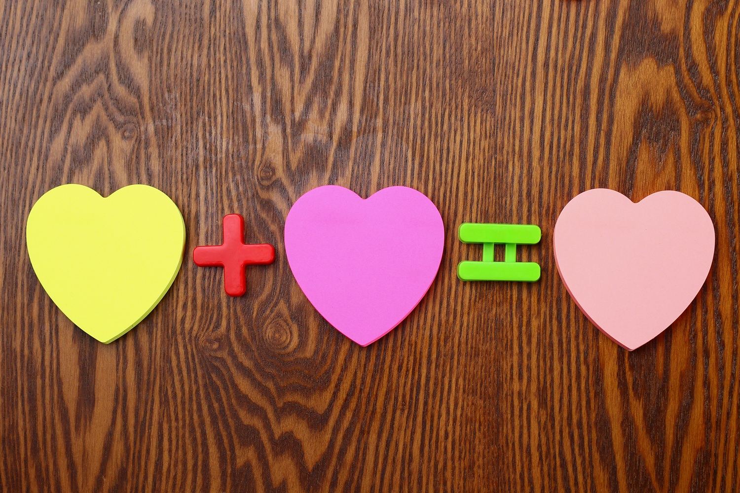 Tres pegatinas en blanco con forma de corazón. Signos matemáticos más e iguales. Concepto de amor.